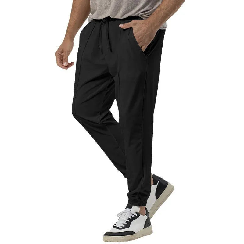 Man wearing grey straight-leg tapered sweatpants, showcasing the mid-rise waist and casual fit.