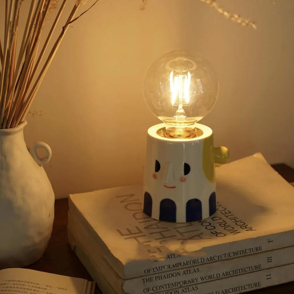 Handmade ceramic bedside lamp with white ball headlight shade on a wooden table.