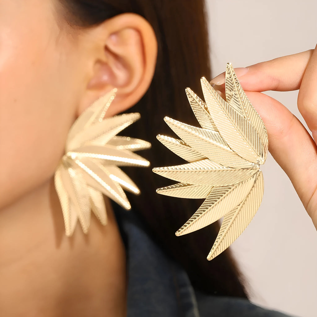 A pair of gold or white alloy earrings shaped like a leaf.