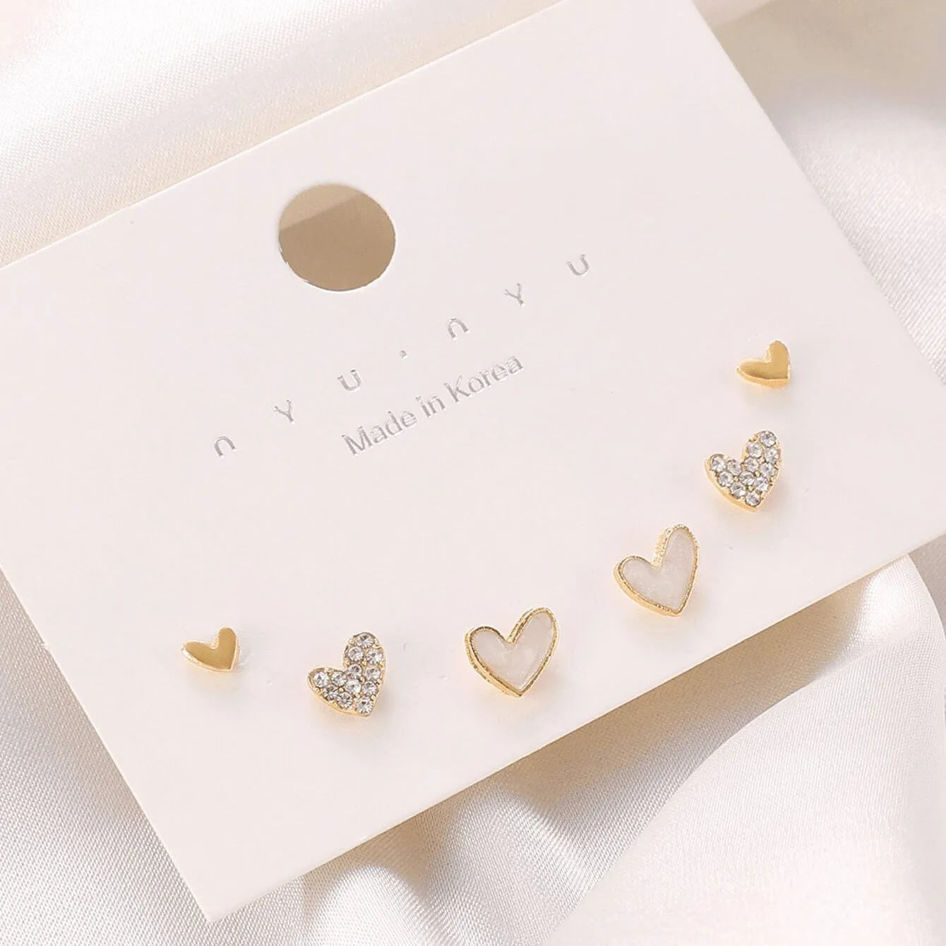Three pairs of girly heart-shaped alloy earrings in gold, black, pink, and black and white colours.