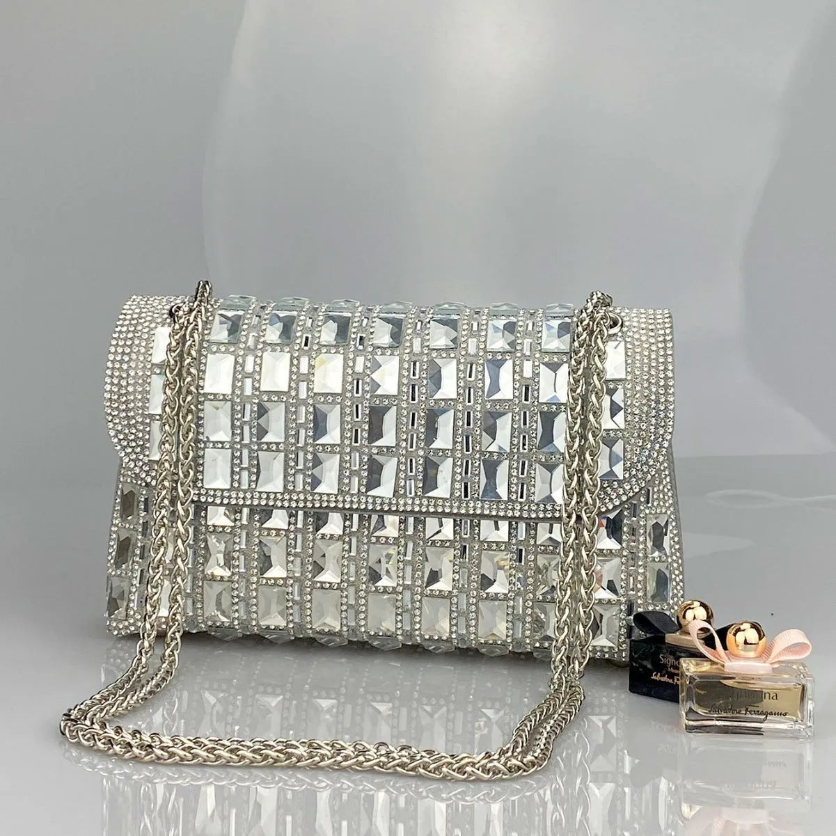 Silver rhinestone chain clutch purse with a horizontal square shape and open pocket.