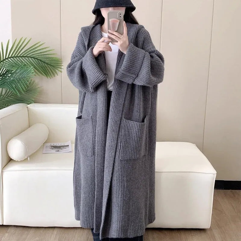 A woman wearing a long, loose, milky white hooded cardigan coat with raglan sleeves.