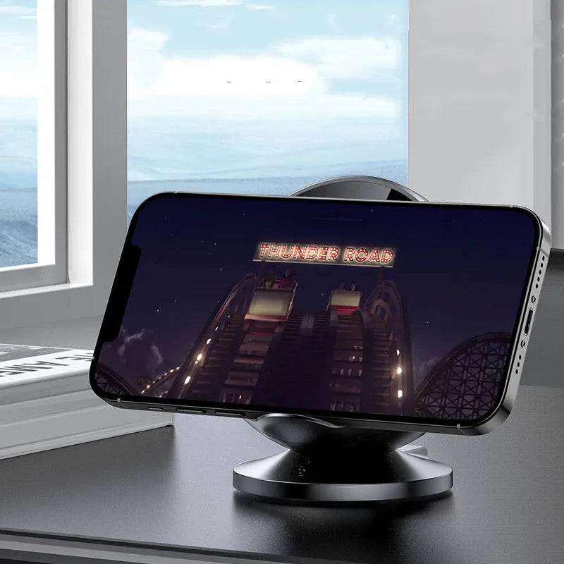 Black multifunctional wireless phone charging holder with integrated Bluetooth speaker on a desk.
