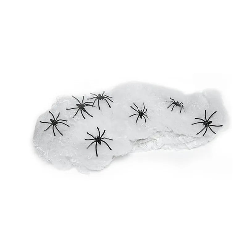 White cotton spider web Halloween decoration with plastic spiders draped over a fence.
