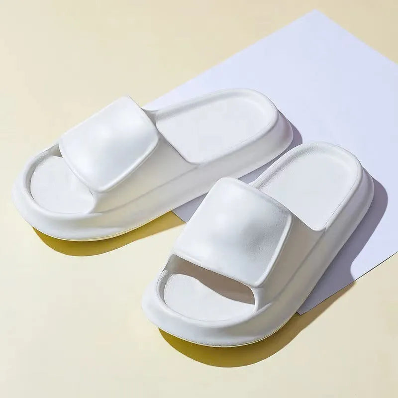 Pair of white EVA flip-flop slippers with a thick, textured sole on a tiled floor.