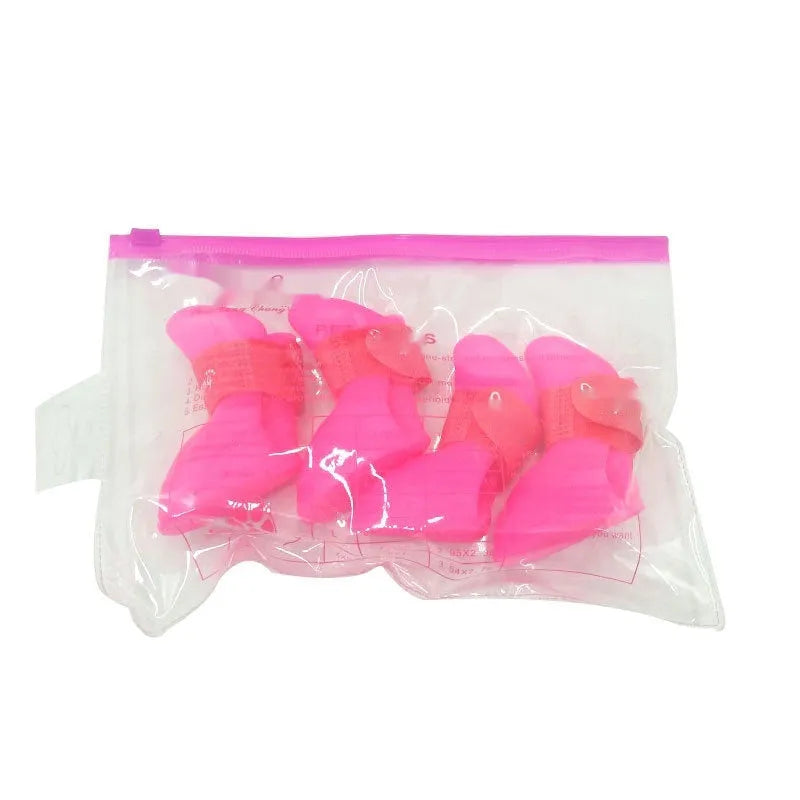 Set of four colourful rubber dog rain shoes with anti-slip soles on a wet surface.