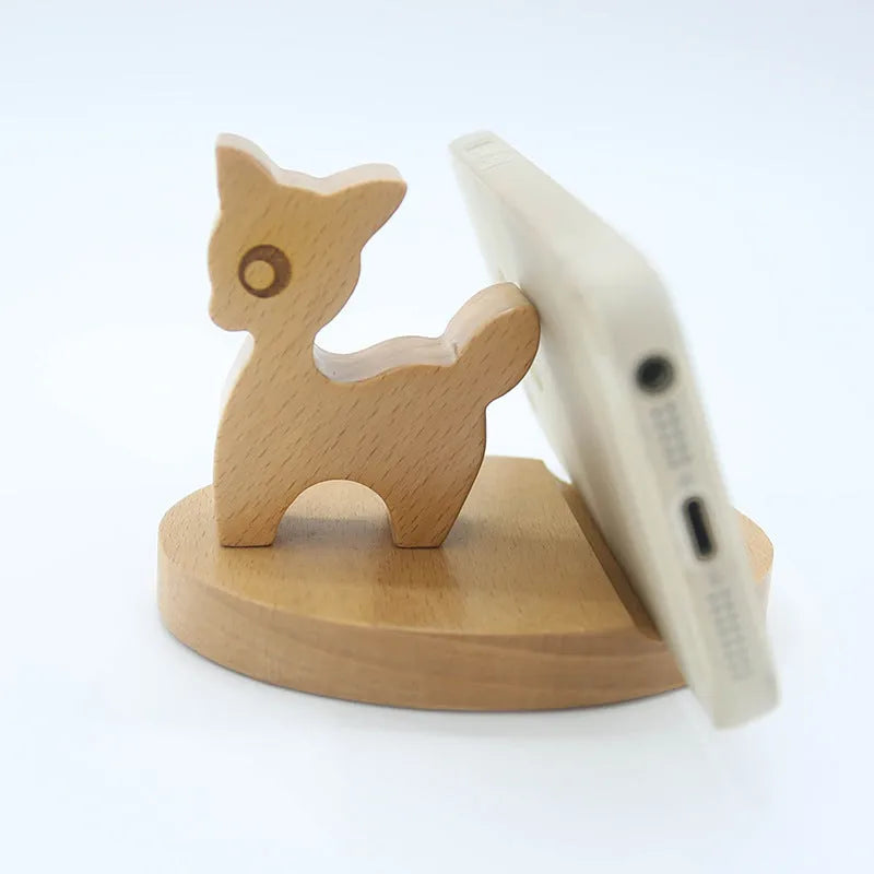 Sculpted beech wood lazy bracket phone holder with custom engraved text on a wooden desk.