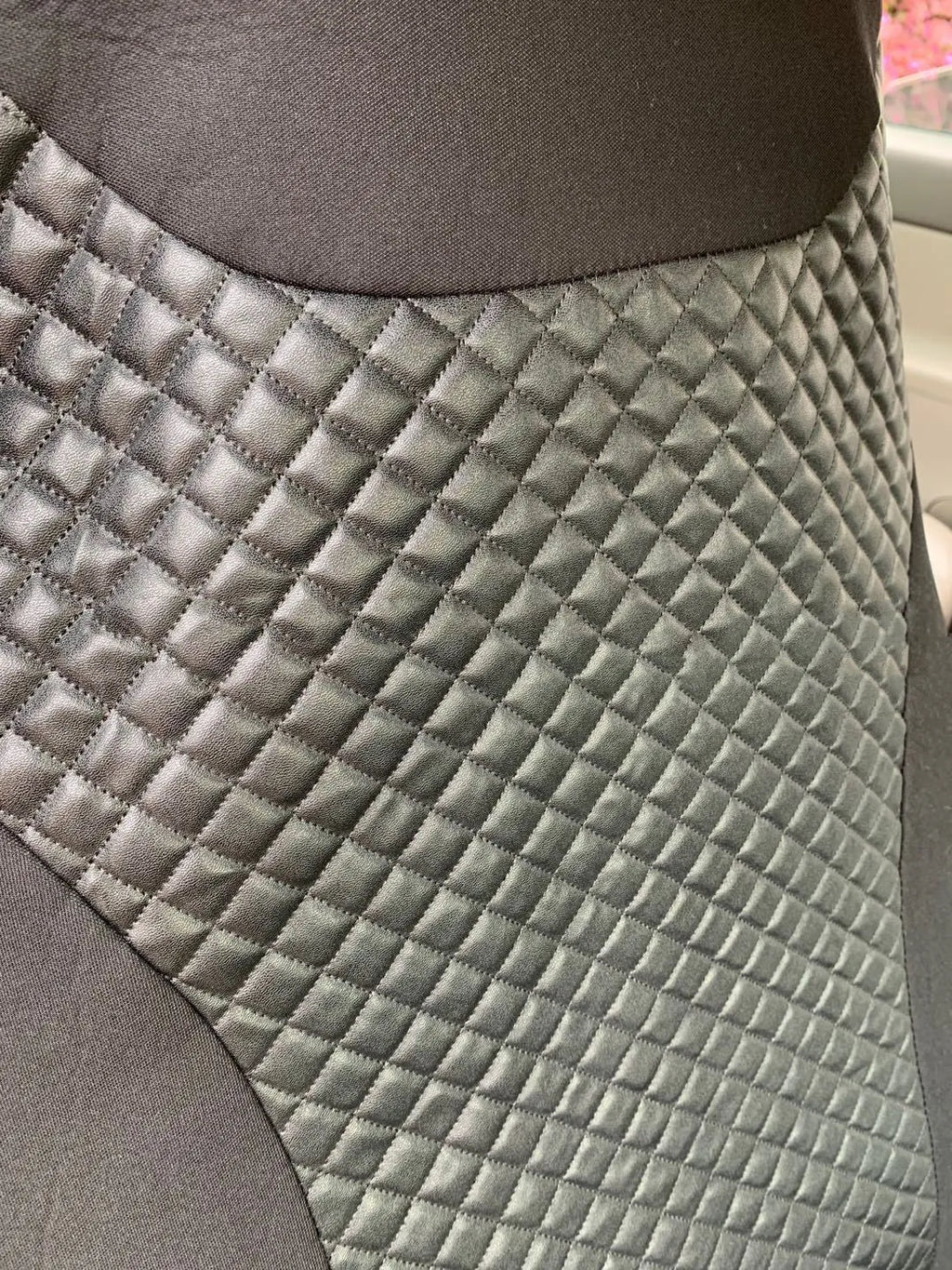 Black quilted automotive seat cover made from PU and polyester fabric, shown with plastic fitting hooks.