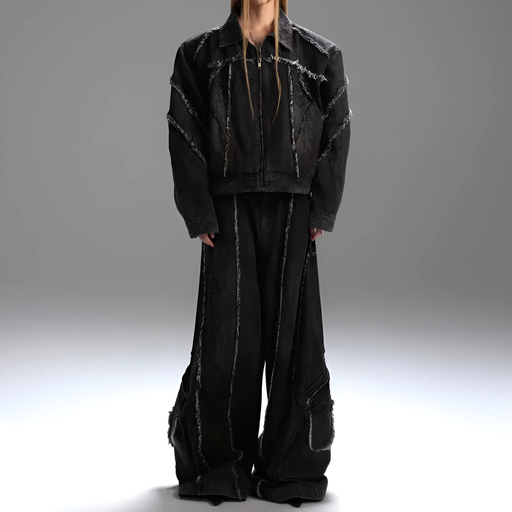 Black raw-edge splash-dye distressed denim coat with padded shoulders and matching trousers on a hanger.