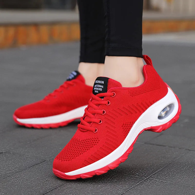 Women's red low-top mesh sneakers with front laces and a round toe, shown on a white background.