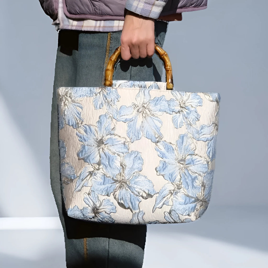 Light blue canvas bag with gold bronzing flower pattern, horizontal square shape, and dual shoulder straps.