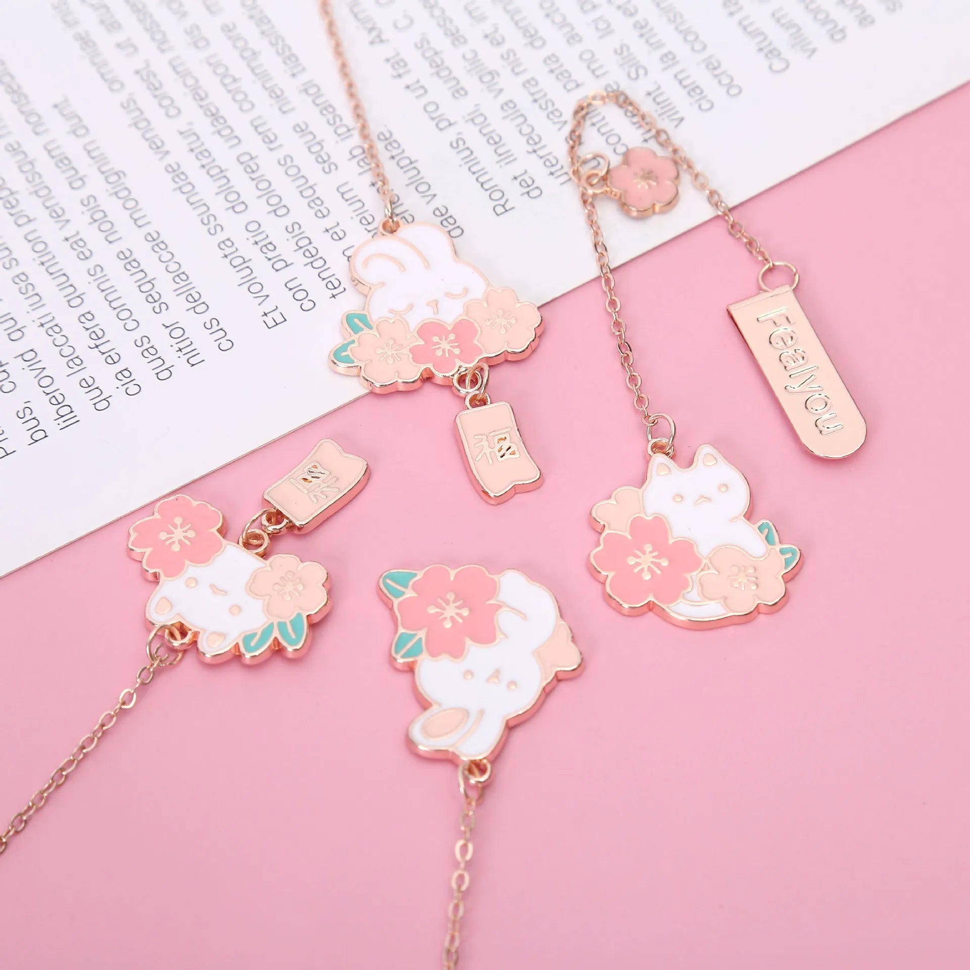 Small metal bookmark pendant with cherry blossom and cartoon cat or rabbit design.