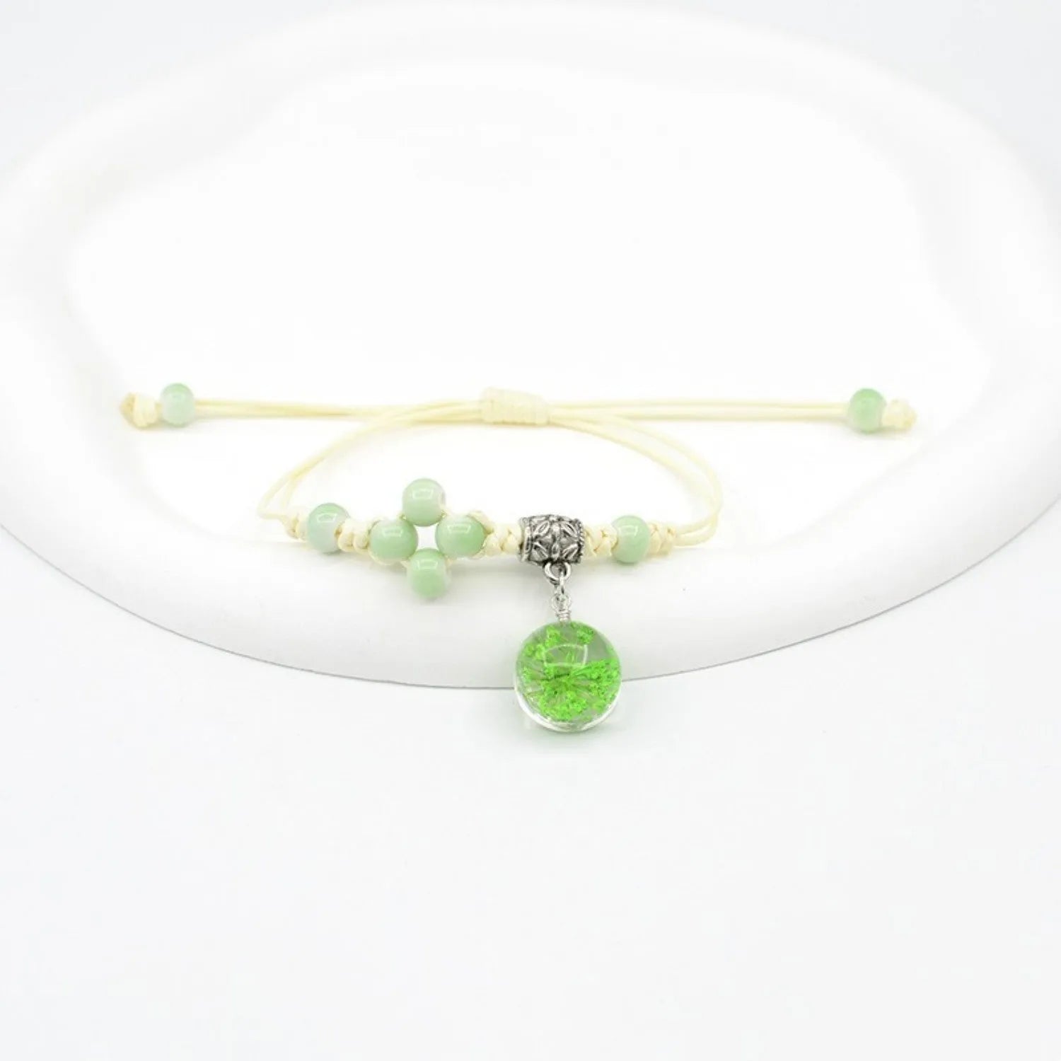 Close-up of a hand-woven glass bracelet with large 1.4cm beads containing real dried flowers and lace floral detailing.