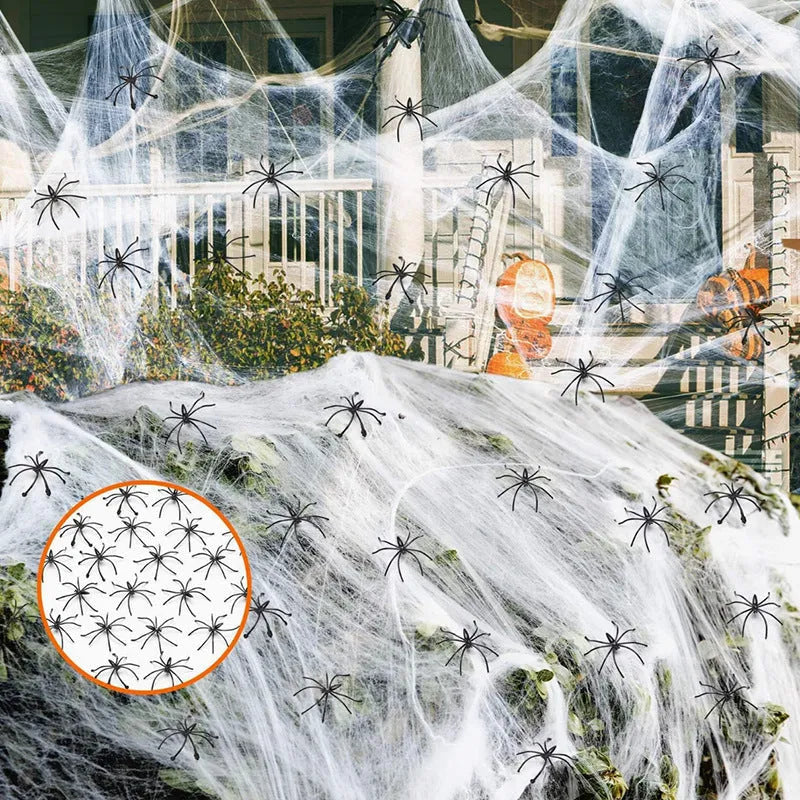 White cotton spider web Halloween decoration with plastic spiders draped over a fence.