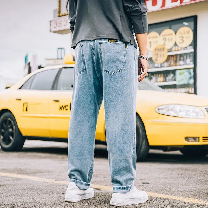 Man wearing dark blue loose straight-leg cotton jeans with a simple design and zipper fly.