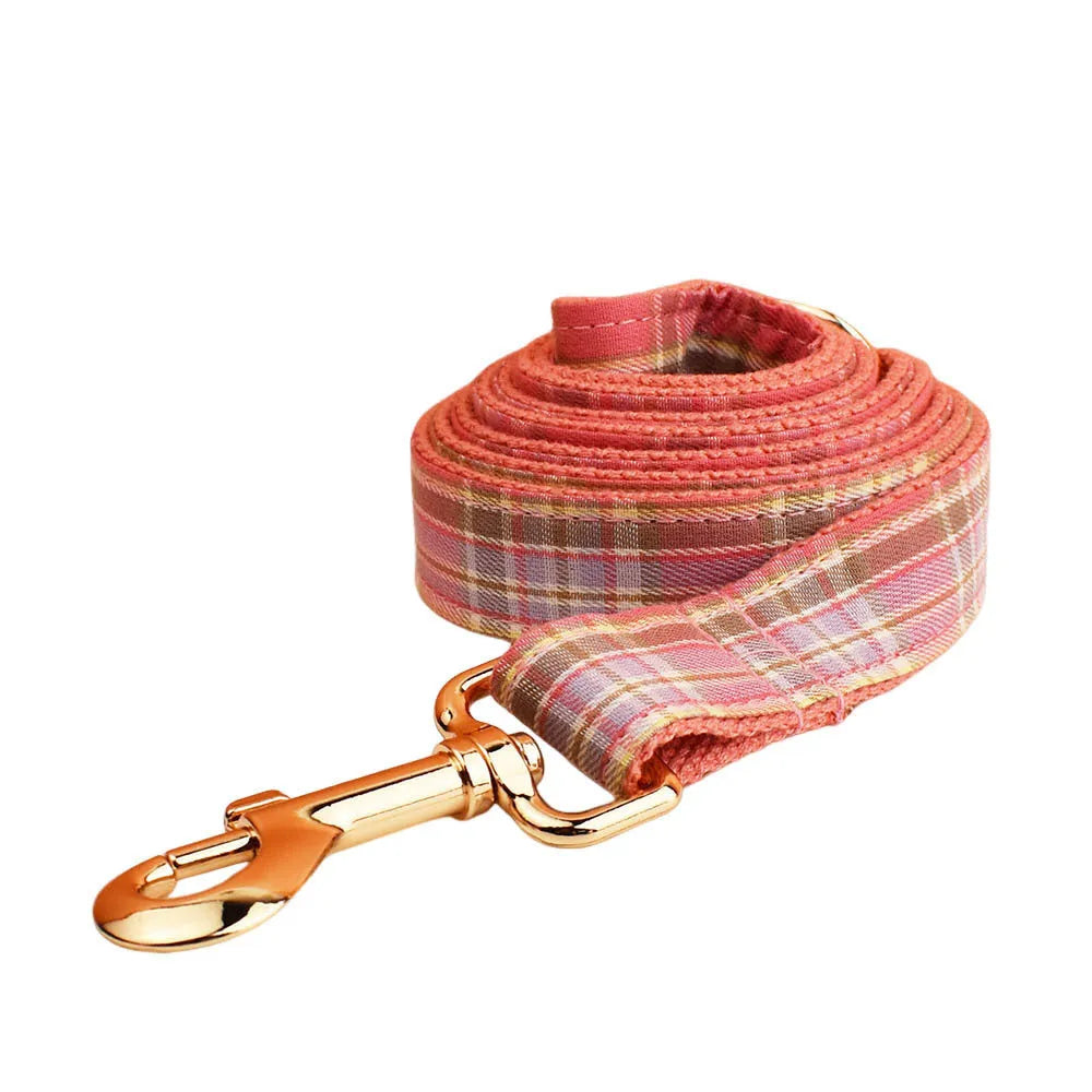 Plaid pattern dog collar and leash set with red bow tie accessory on cloth fabric