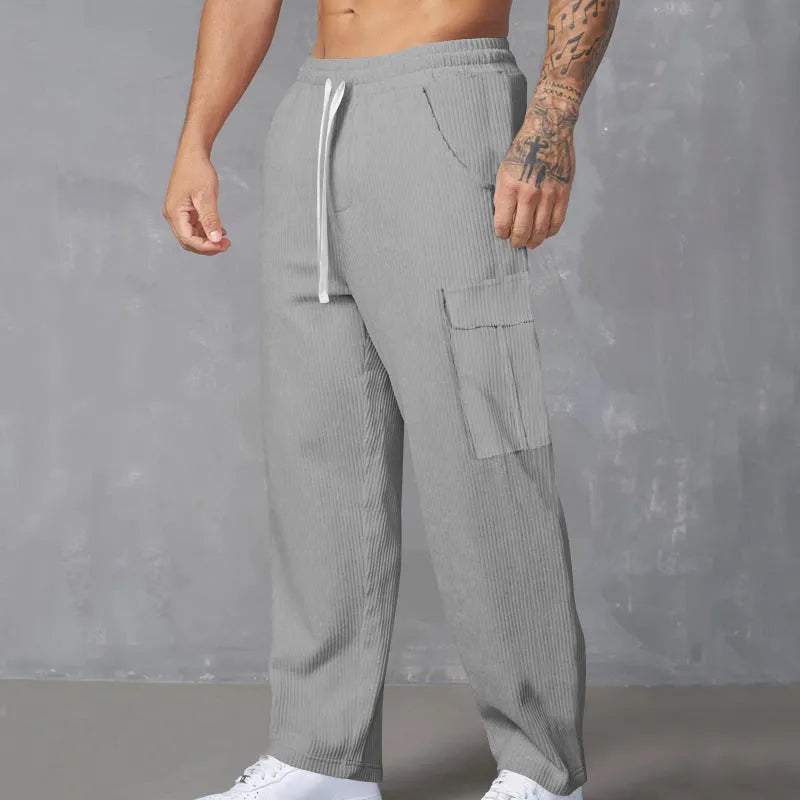Man wearing navy blue loose-fit corduroy cargo trousers with a drawstring waist.