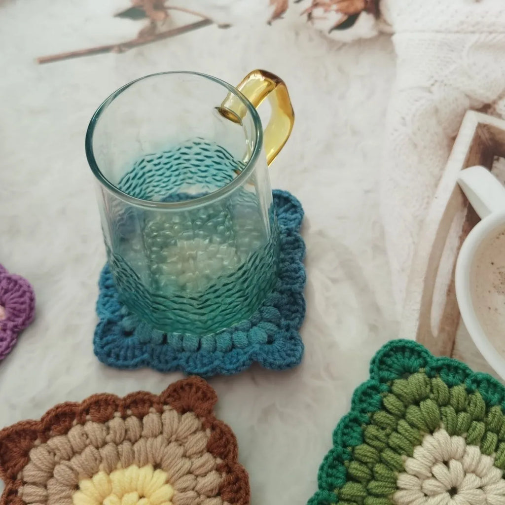 Square crocheted wool placemat with Grandmother Lattice pattern for cup heat protection.