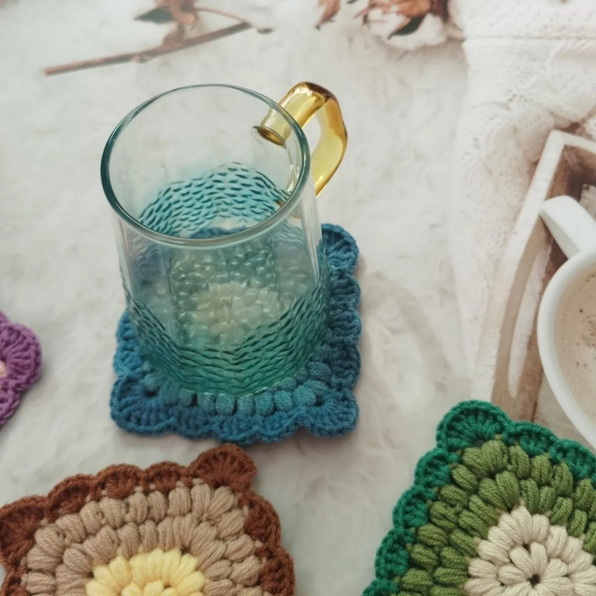 Square crocheted wool placemat with Grandmother Lattice pattern for cup heat protection.