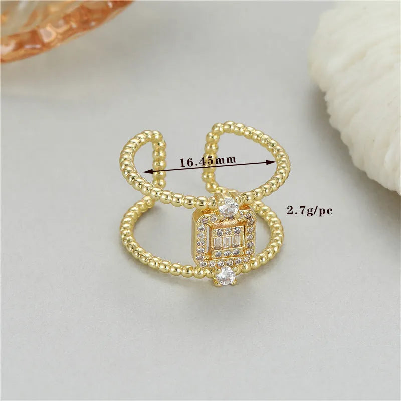 Gold-coloured adjustable open ring with a U-shaped asymmetric design on a hand.