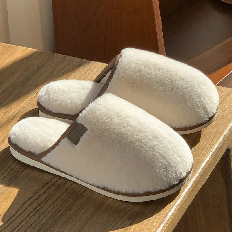 Pair of solid-colour plush winter slippers with a slip-on design and a textured PVC sole.