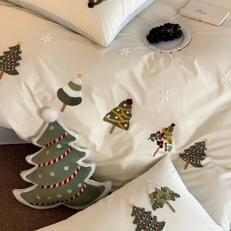 Cream blue cotton duvet cover with embroidered Christmas tree and floral design, laid on a bed with matching pillowcases.
