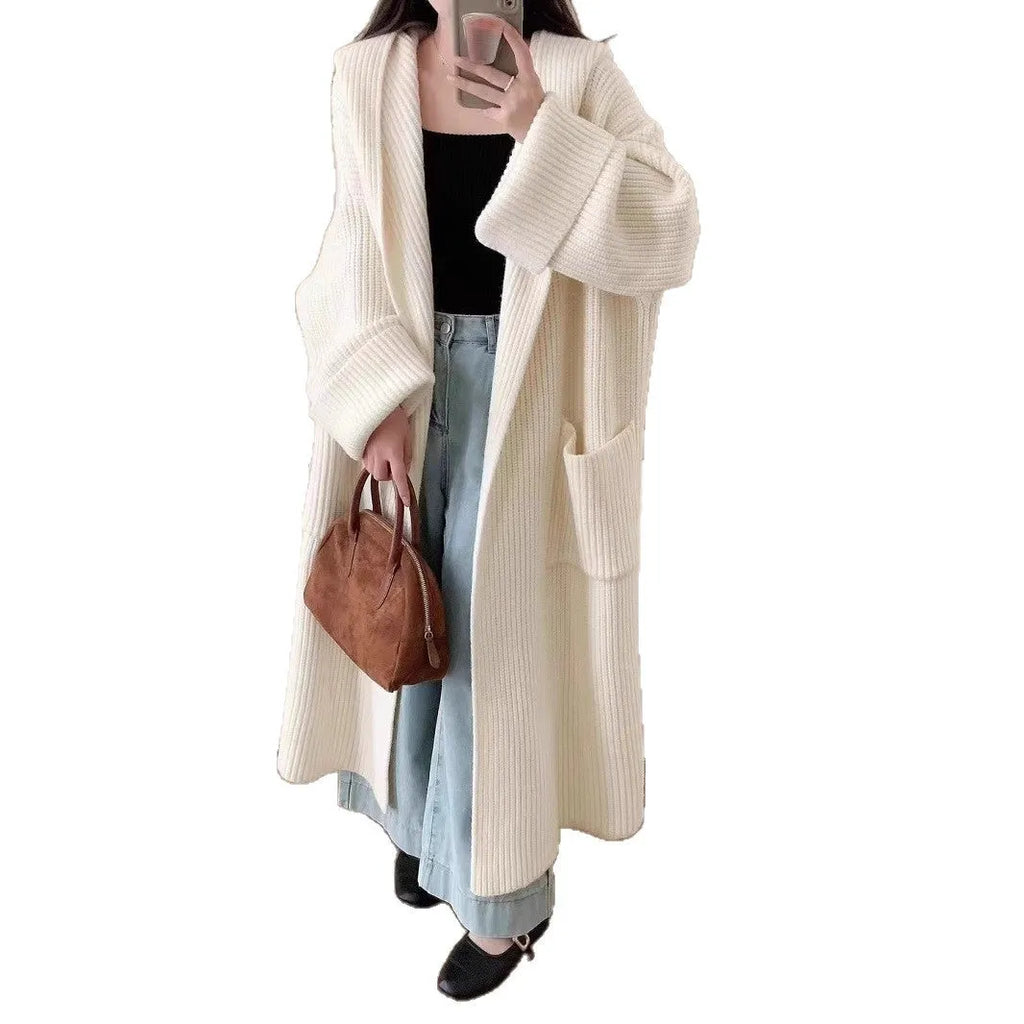 A woman wearing a long, loose, milky white hooded cardigan coat with raglan sleeves.