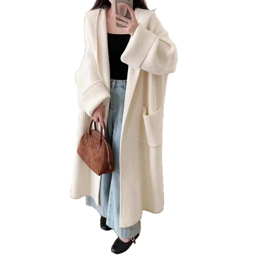 A woman wearing a long, loose, milky white hooded cardigan coat with raglan sleeves.