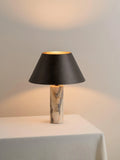 Black modern minimalist table lamp with a solid marble base on a wooden surface.
