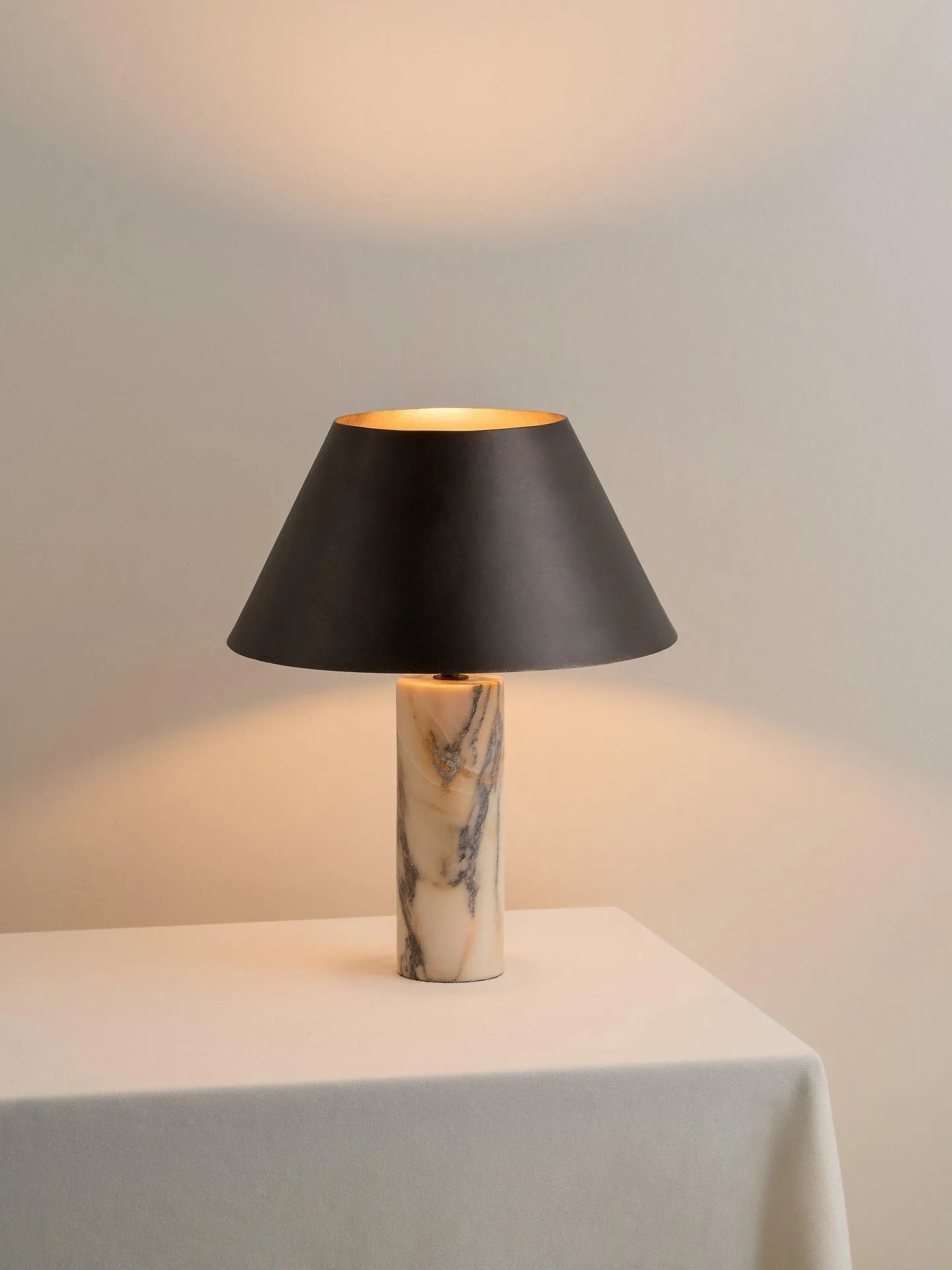 Black modern minimalist table lamp with a solid marble base on a wooden surface.
