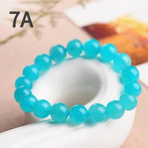 Natural blue-green Grade 7A Amazonite scattered beads in various sizes next to a finished crystal bracelet.