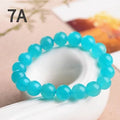 Natural blue-green Grade 7A Amazonite scattered beads in various sizes next to a finished crystal bracelet.