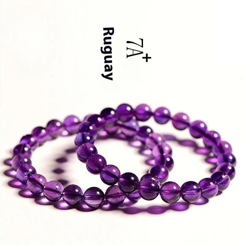 Close-up of a polished natural amethyst bead bracelet with a sliding knot closure on a wrist.