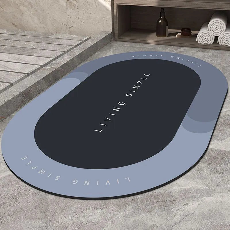 Oval grey polyester door mat with textured rubber non-slip backing on a wooden floor.