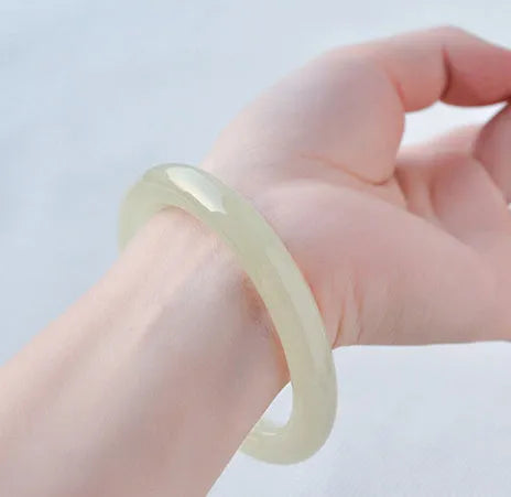 A close-up of a winding jade bracelet made from round bar beads on a wrist.