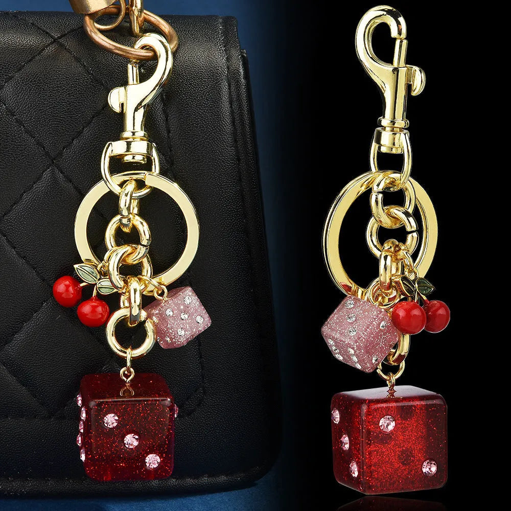 Square cherry red and silver two-tone dice keychain pendant with metal keyring on a grey background