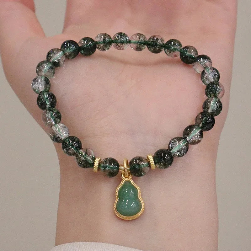 Handmade women's bracelet with a heart-shaped green phantom quartz pendant and pearl details on a crystal chain.