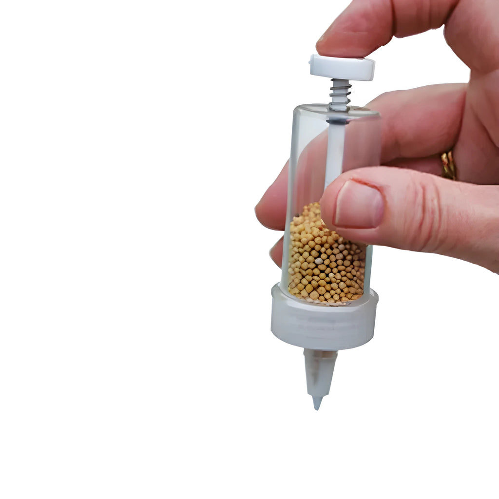 A white plastic mini garden seeder tool, 12cm long, for planting seeds in pots and trays.