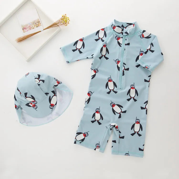 Boy's penguin print long sleeve swimsuit top and matching swim cap set on blue background