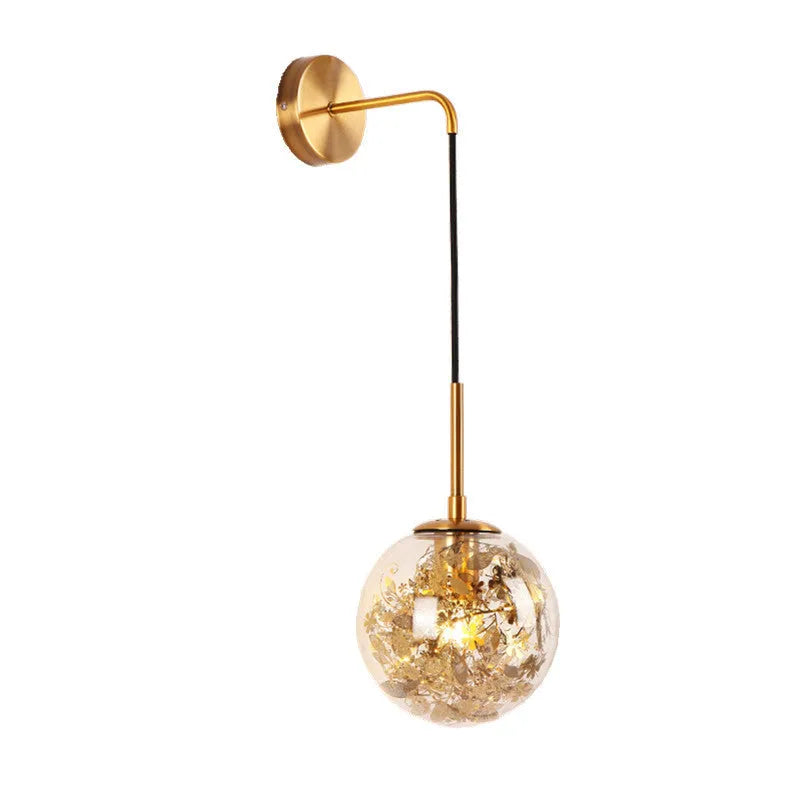 Modern small glass wall lamp in golden flower finish mounted on a bedroom wall.