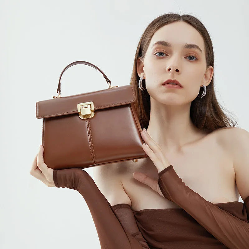Black genuine leather women's shoulder bag with vachette clasp, showing horizontal square shape and adjustable strap.