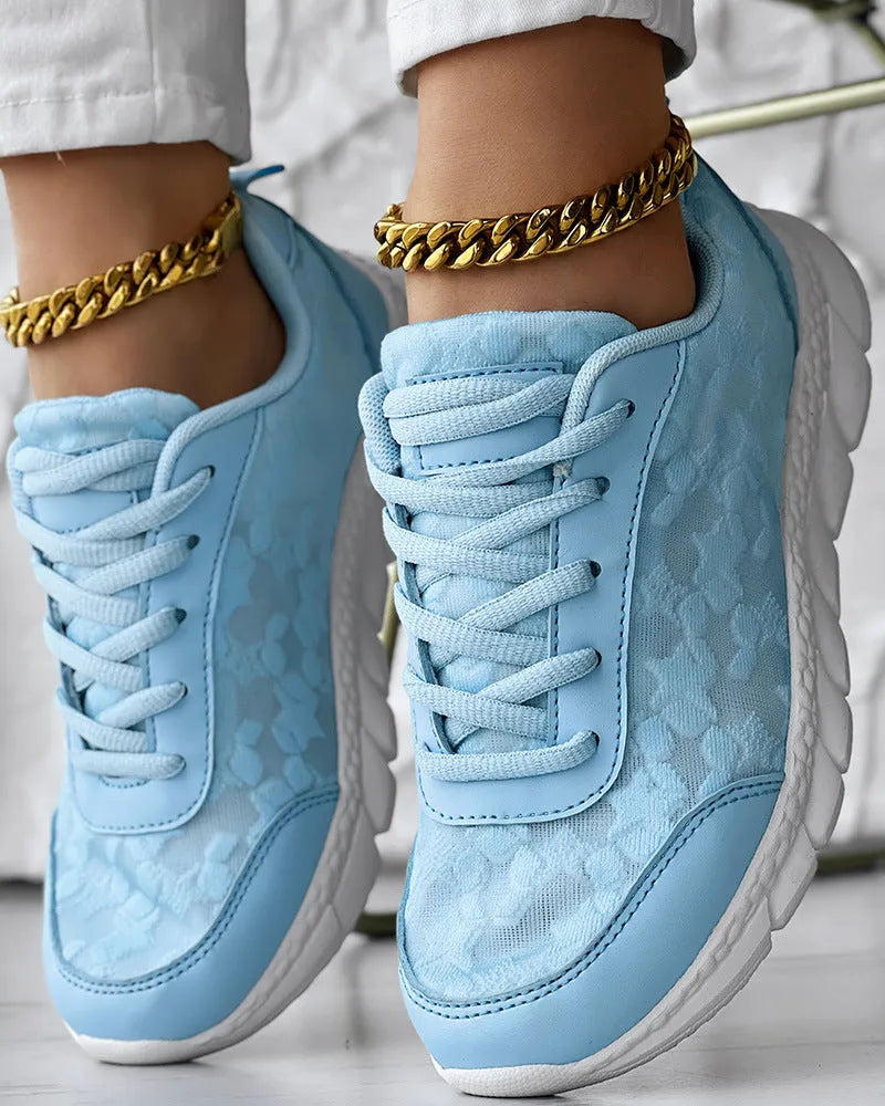 Women's white canvas running shoes with a flat heel and round toe on a plain background.