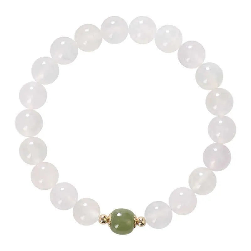Handmade natural white agate and crystal bracelet with red cinnabar inlays on a wrist.