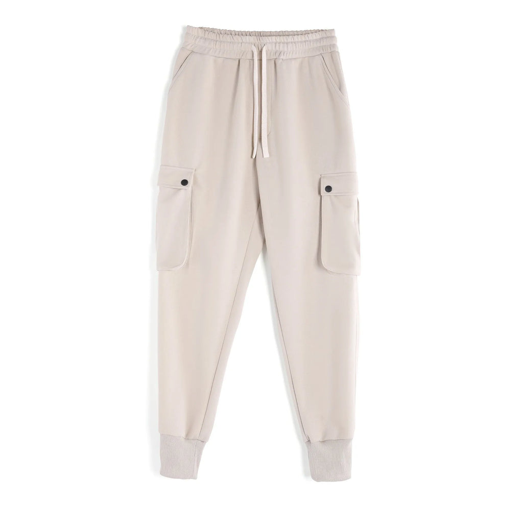 Men's loose-fit light grey cotton trousers with tapered legs and tied ankle cuffs, showing multi-pocket detail.