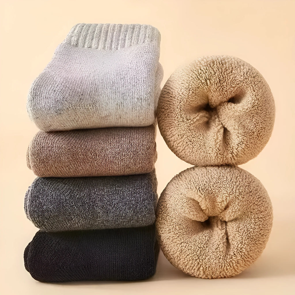 Pair of thick grey wool socks with a reinforced midsole, folded next to their storage box.