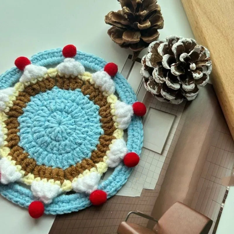 Circular wool felt coaster with cake design, 9 cm in diameter, shown on a table.