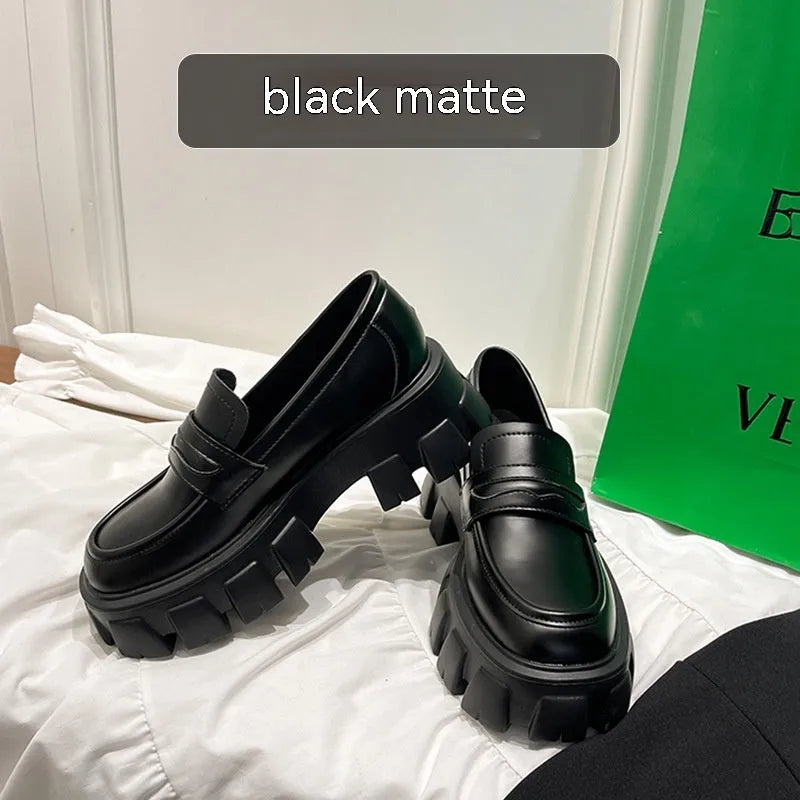 A pair of wide fit patent leather loafers with a flat rubber sole on a neutral background.
