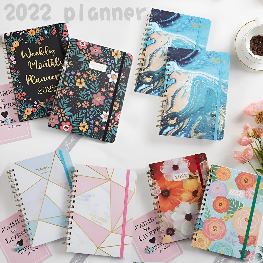 A5 spiral notebook with colourful floral cover design, lying open on a table.