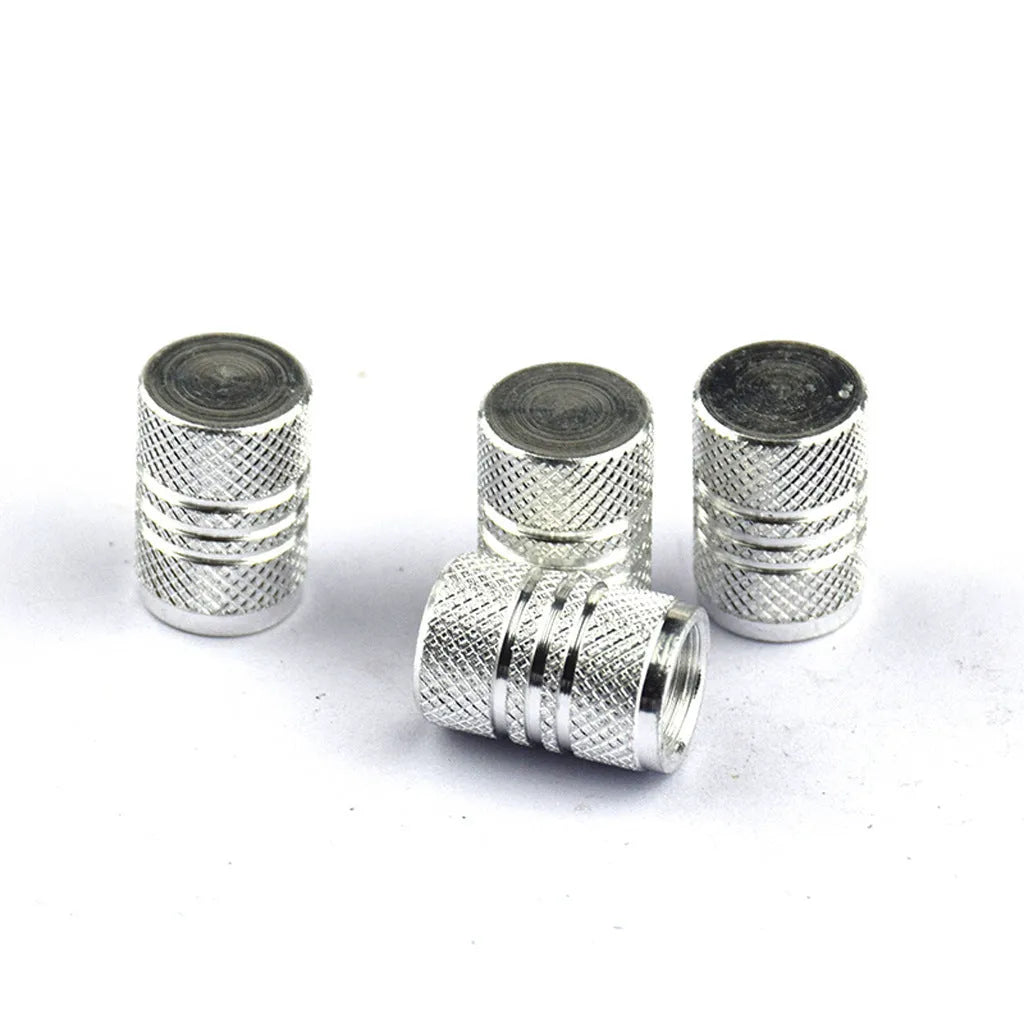 Set of coloured aluminium alloy tyre valve caps for car wheels on a grey background.