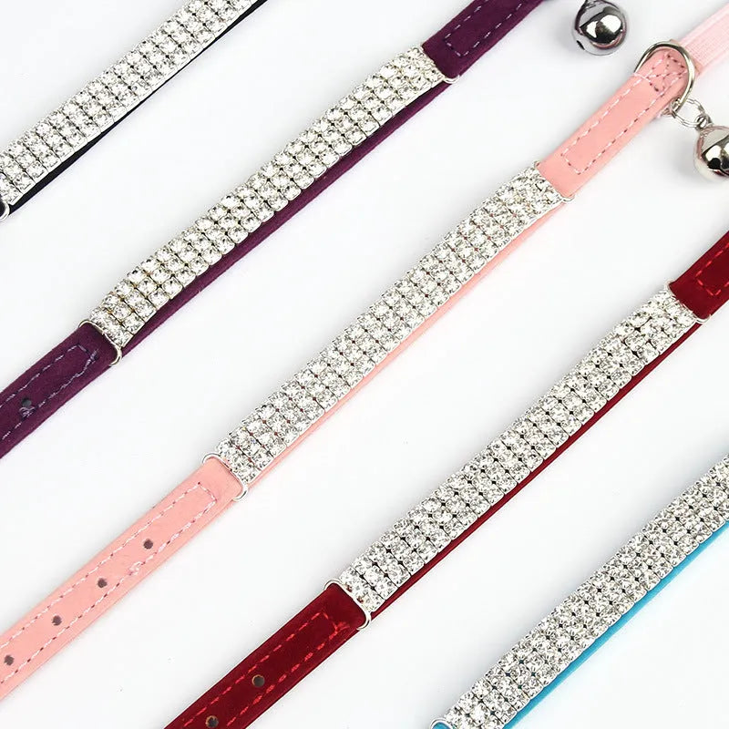 A red velvet cat collar with sparkling rhinestones, shown adjusted to fit, on a neutral background.